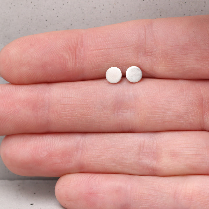 5mm sterling silver circle stud earrings shown on hand for scale