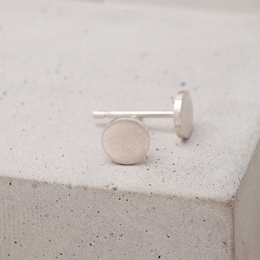 Handmade sterling silver circle stud earrings shown from the side