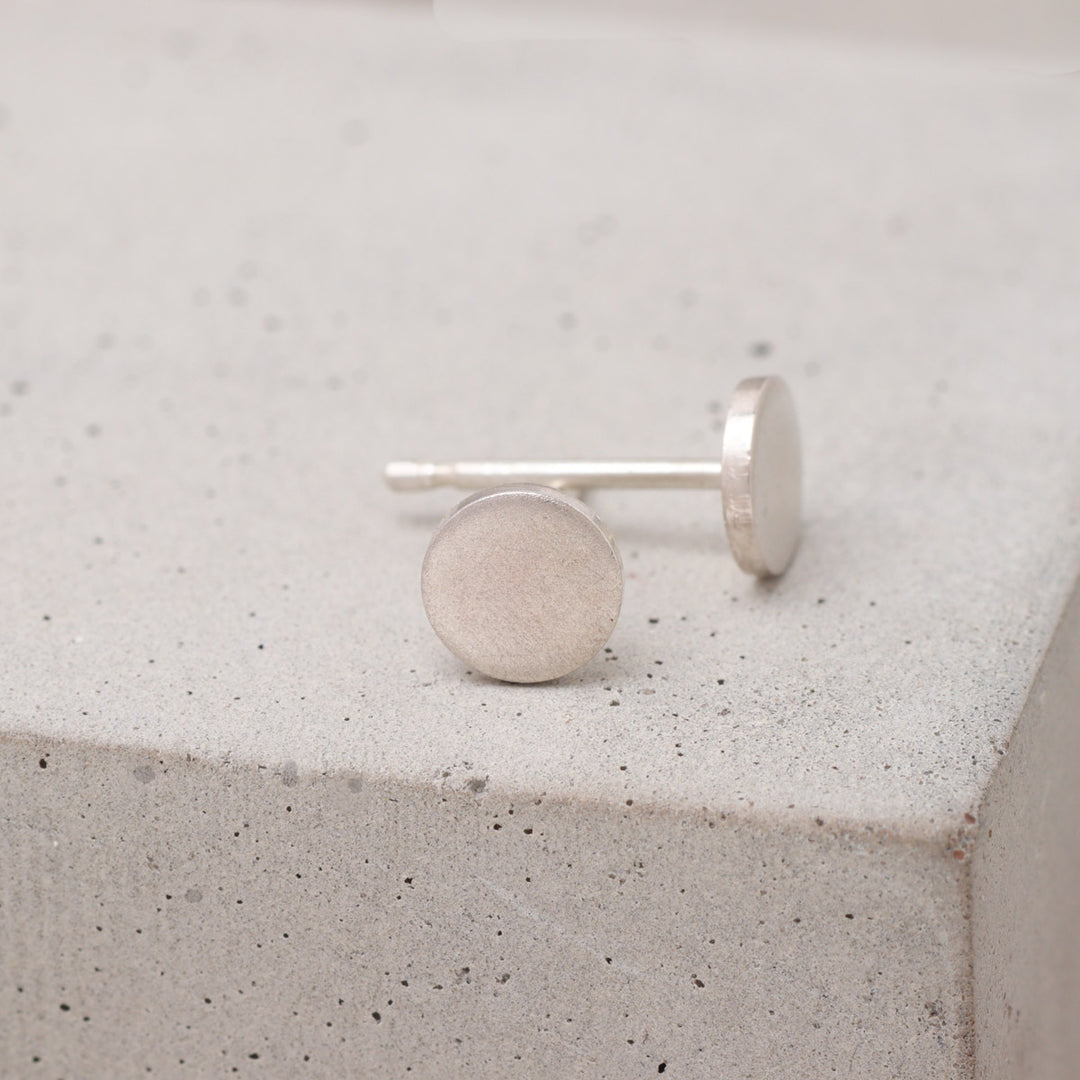 Handmade sterling silver circle stud earrings shown from the side