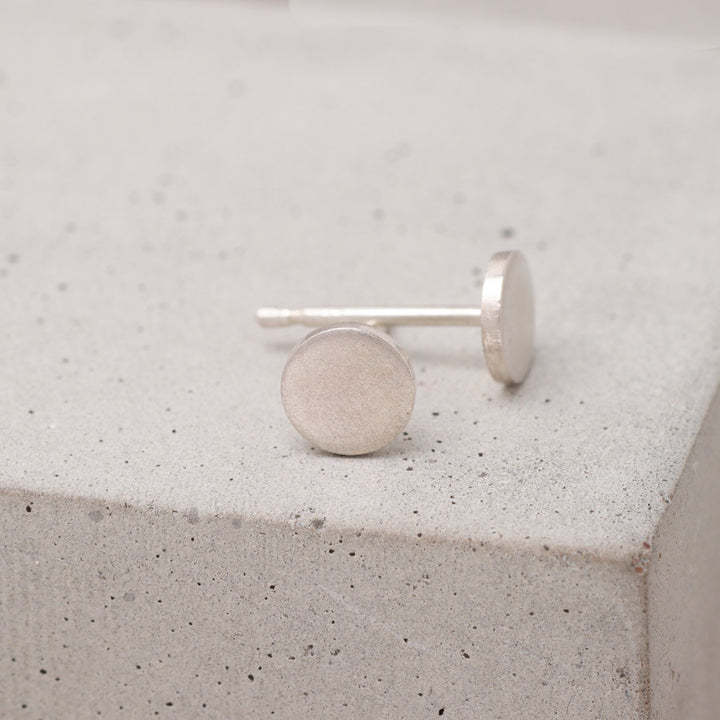 Handmade sterling silver circle stud earrings shown from the side