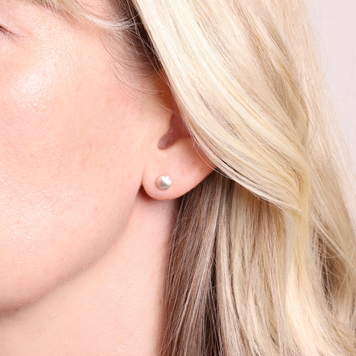 Medium frosted silver stud earrings worn on the ear
