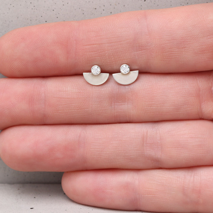Sterling silver and moissanite stud earrings shown on hand for scale