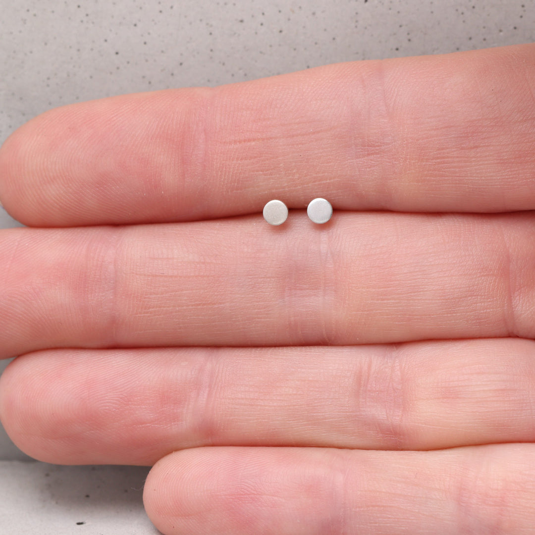 3mm sterling silver circle stud earrings shown on hand for scale